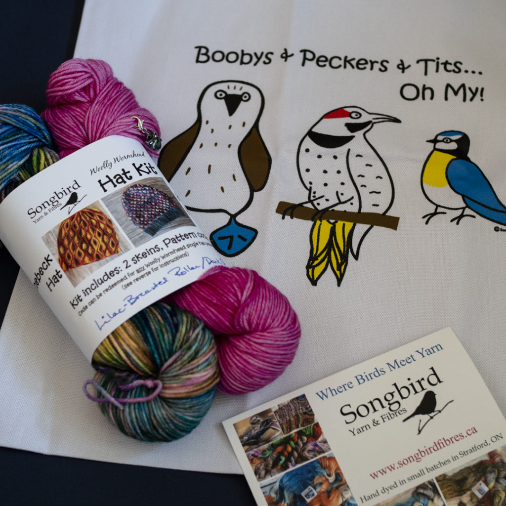 Songbird Yarn and Fibres gift set with yarn and tote bag. Tote bag has drawings of birds and reads "Boobys & Peckers & Tits… oh my!"